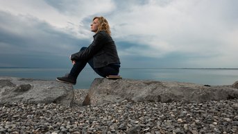 Thoughtful woman sitting on rocks