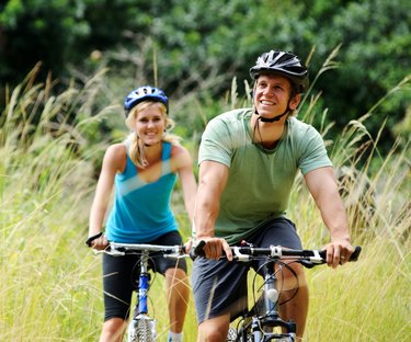 Young couple bike riding through a grassy field