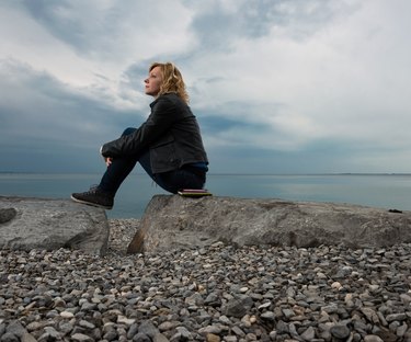 Thoughtful woman sitting on rocks