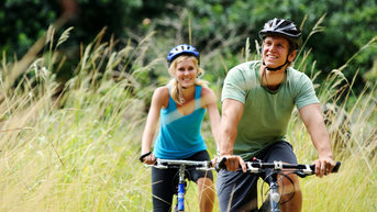 Young couple bike riding through a field