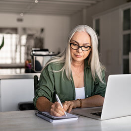 Woman taking detailed notes from laptop